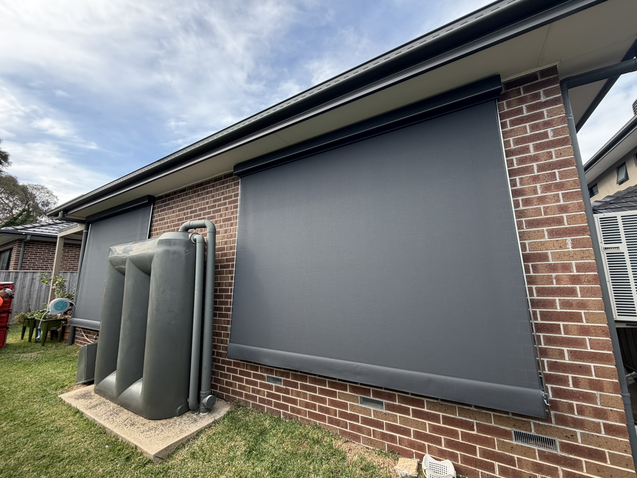 Charcoal fixed guide awning installed on a brick home