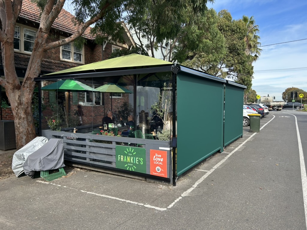 Straight drop blinds enclosing a cafe outdoor dining area with clear PVC and green mesh fabric