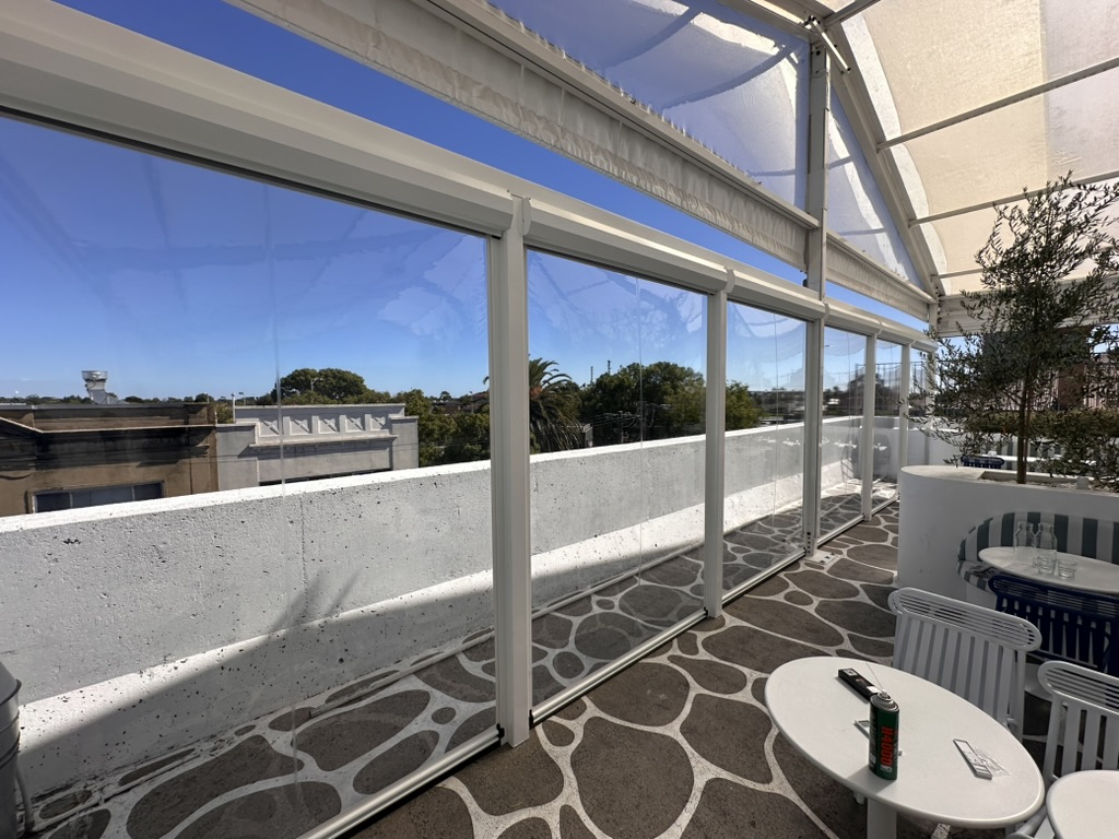 Clear PVC Ziptrak blinds enclosing a bright commercial terrace